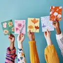 A diverse group holding colourful greeting cards